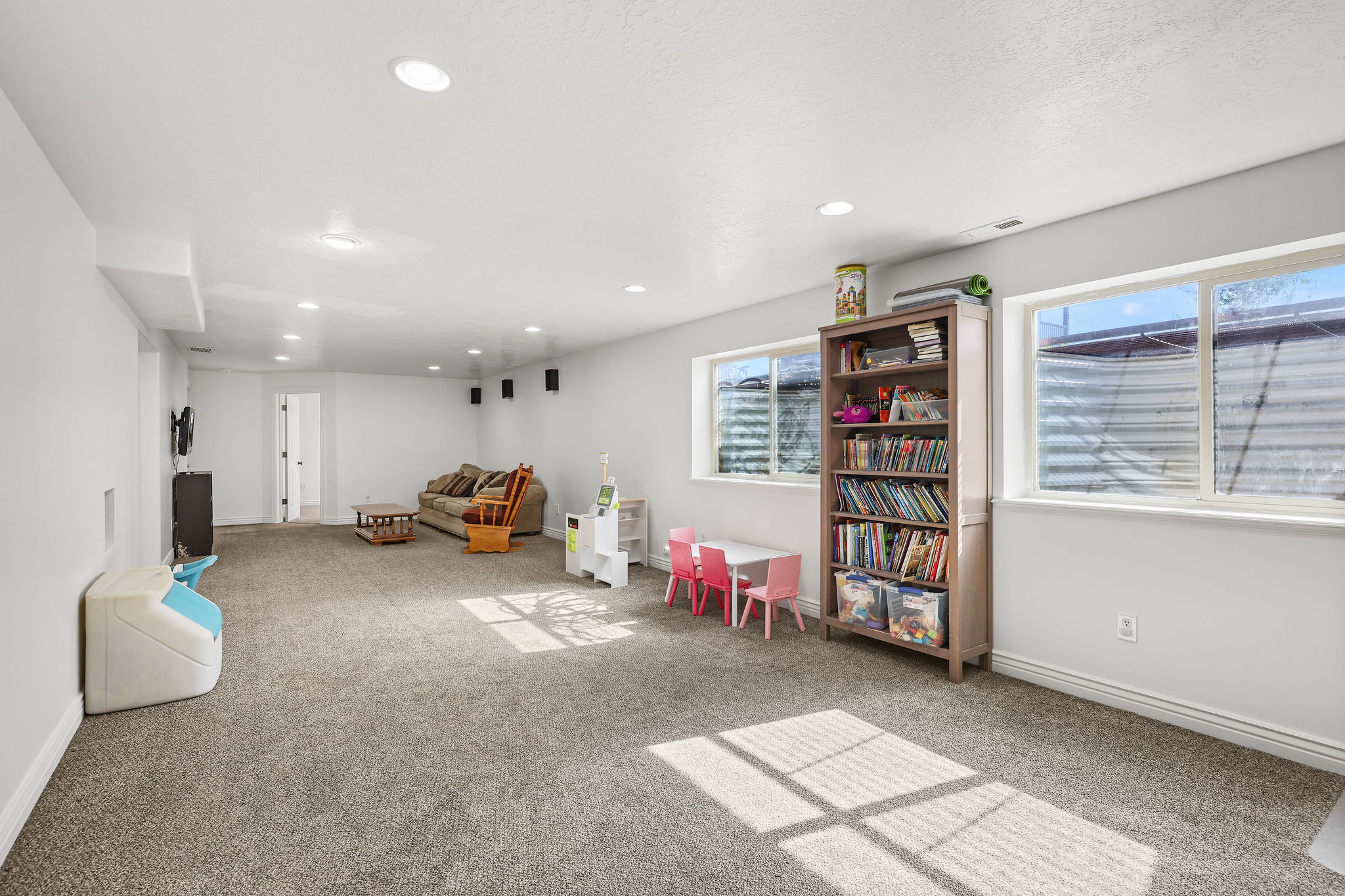 Spacious finished basement with recessed lighting, light gray carpeting, and two egress windows
