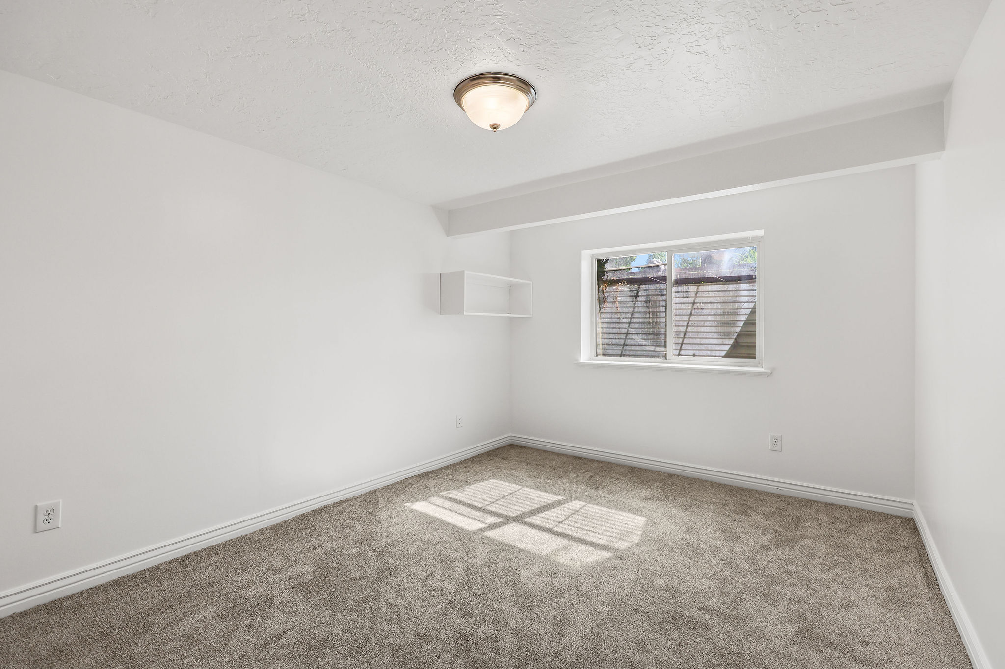 Interior room featuring neutral-toned carpet, white walls, and a single window