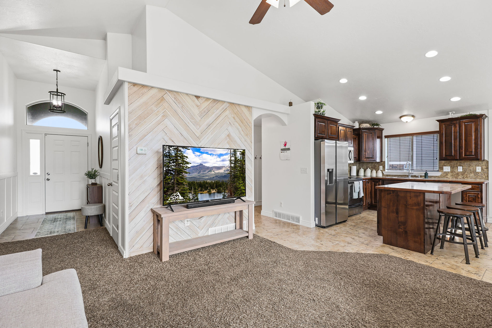 Open-concept living area with vaulted ceilings and a chevron wood-finish accent wall