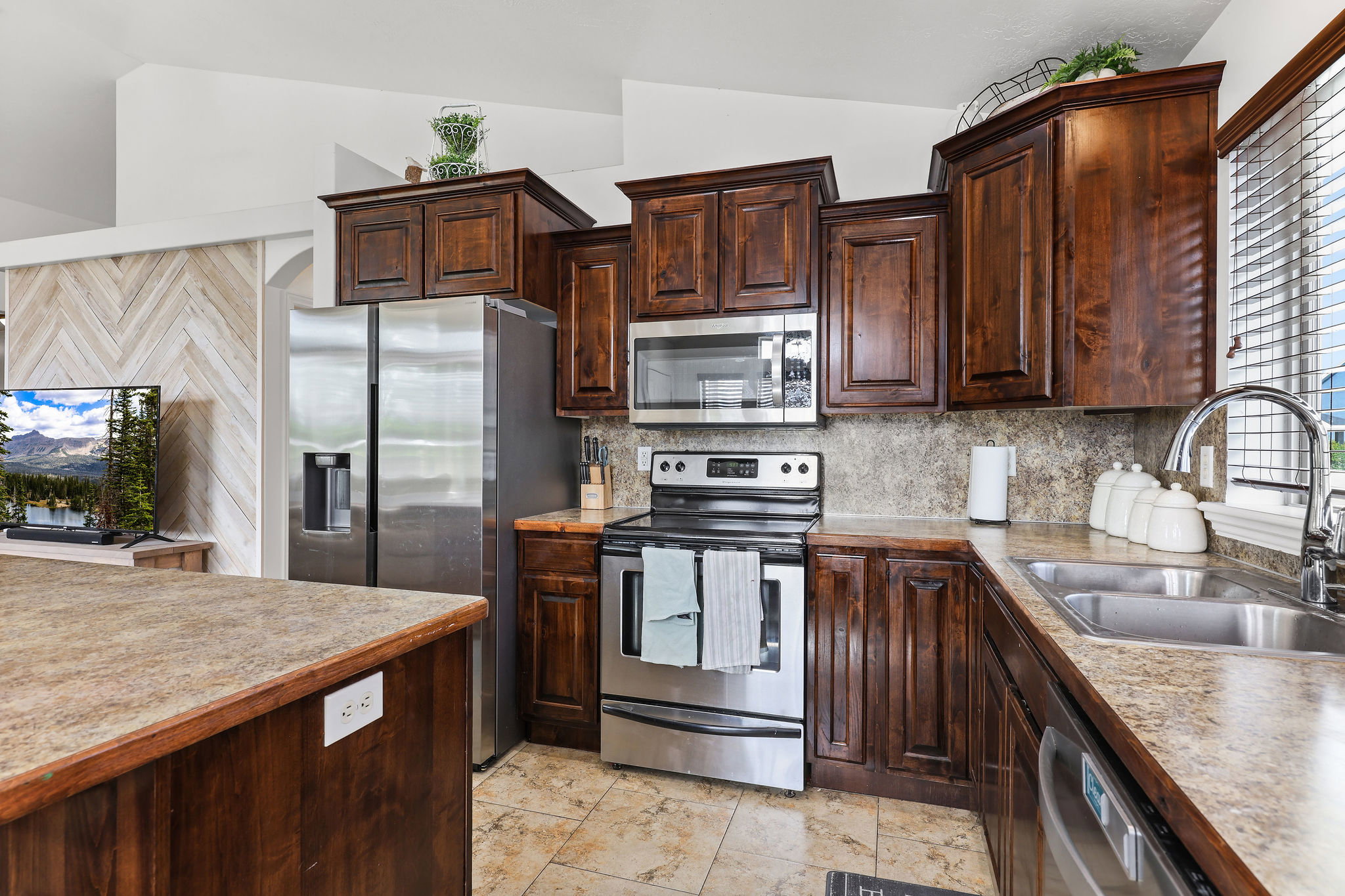 Kitchen with wood cabinetry, stainless steel appliances, and stone-look countertops