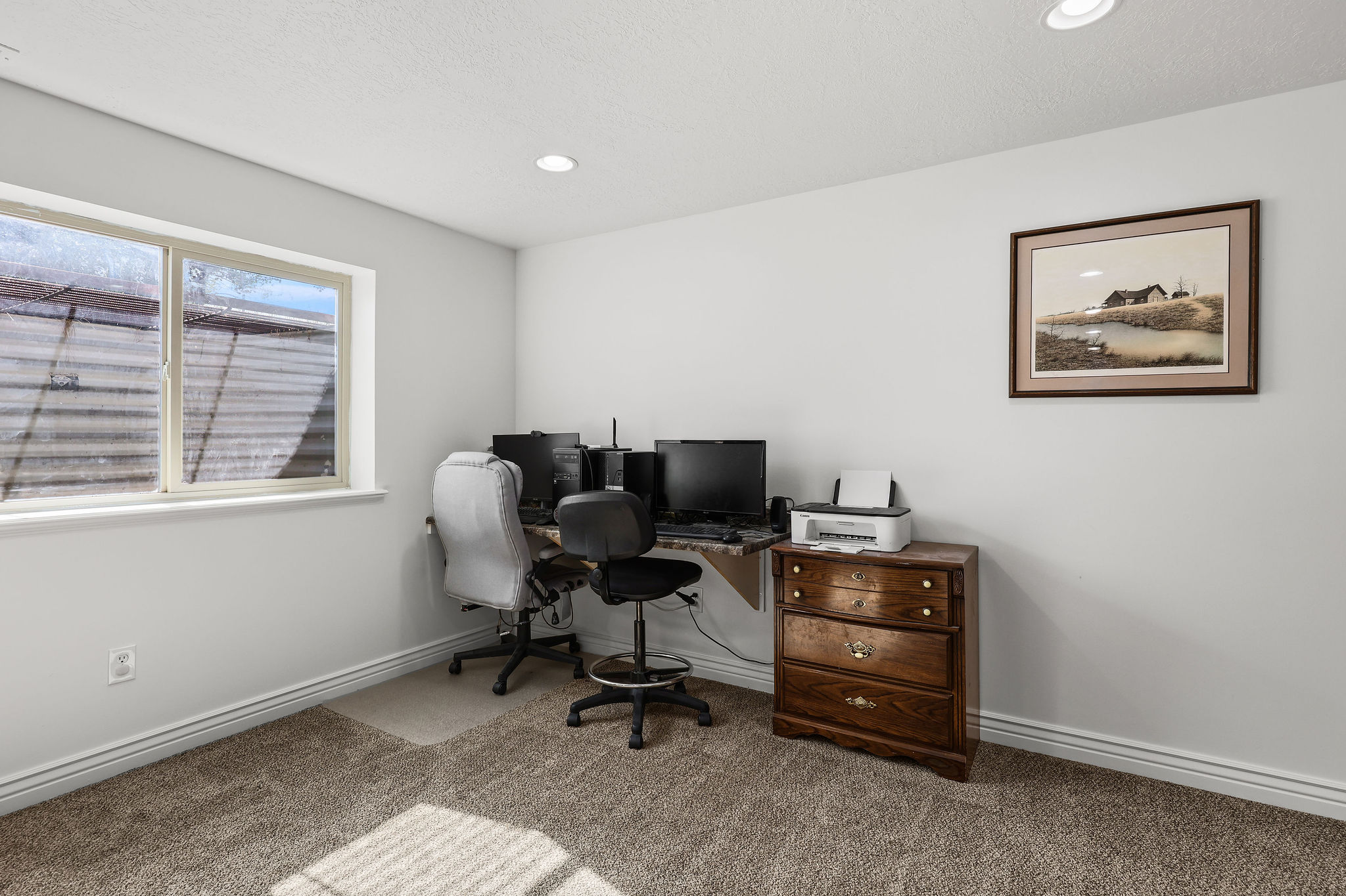 Carpeted room with a single window and recessed lighting