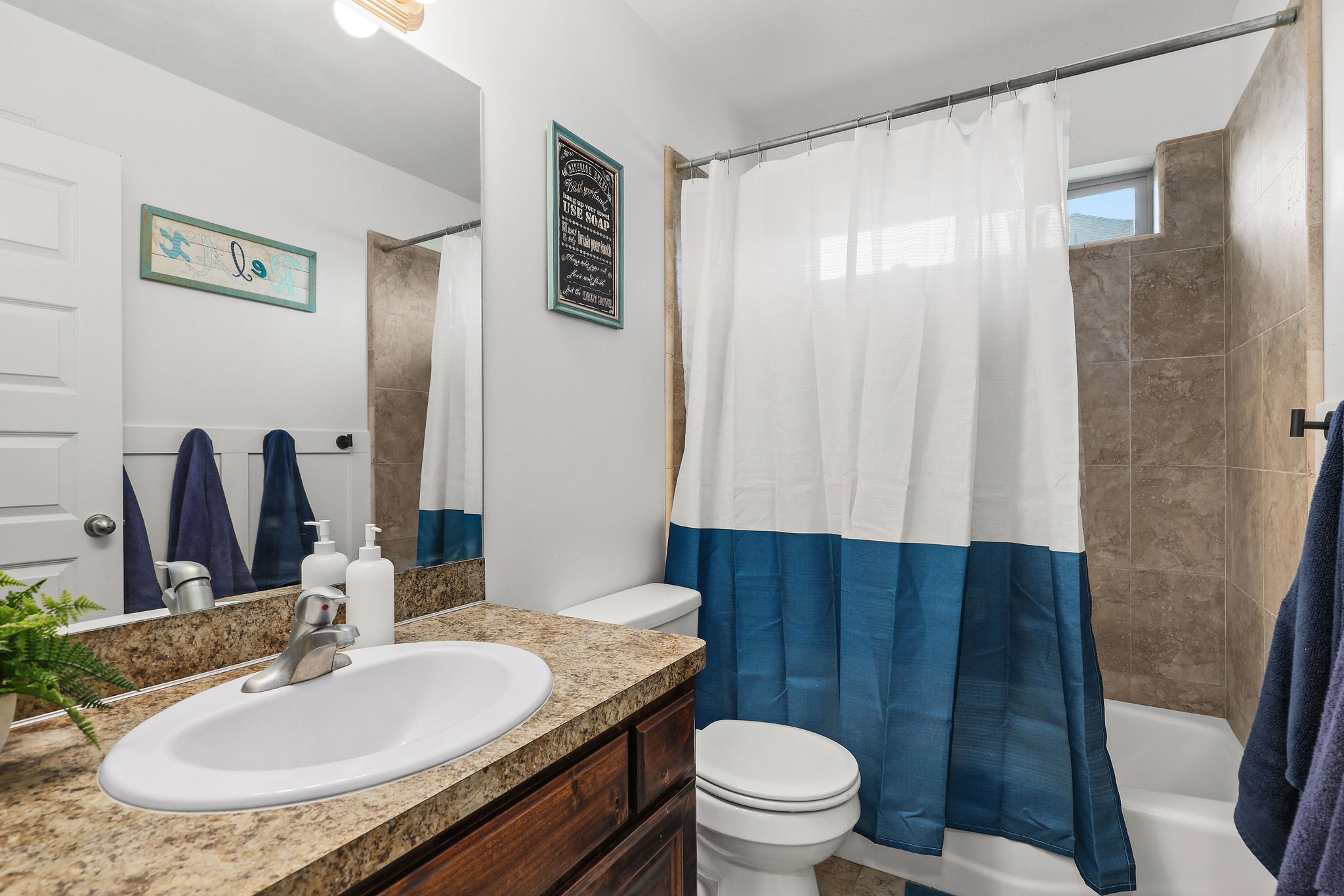 Bathroom featuring a wood-finish vanity with an integrated oval sink, a speckled countertop, and a large wall-mounted mirror