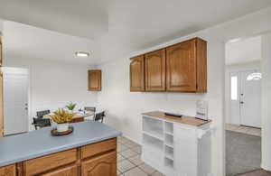 Kitchen featuring wood-finish cabinetry, light countertops, and square tile flooring