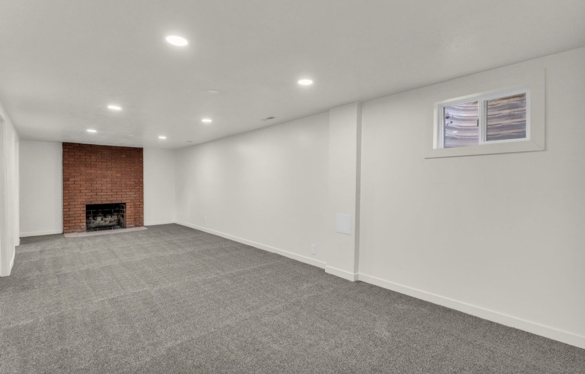 Spacious room featuring a brick fireplace, recessed lighting, and grey carpet flooring