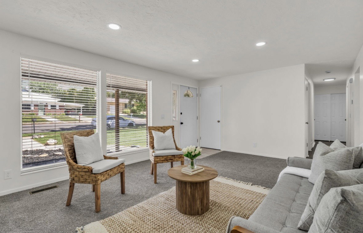 Bright living area featuring large windows with blinds, recessed lighting, and neutral carpet flooring