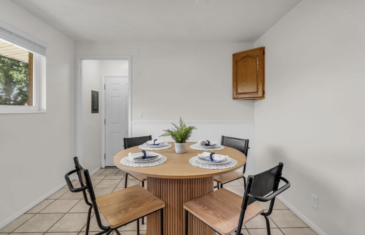 Dining area featuring tile flooring, wainscoting, and a wood-finish wall cabinet