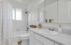 Bathroom featuring a white vanity with an undermount sink, a stone-finish countertop, and a mirrored medicine cabinet