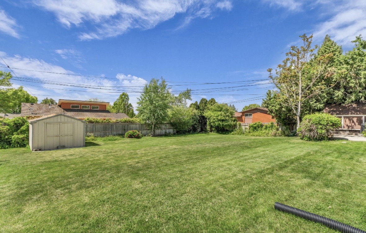 Expansive lawn area featuring a storage shed and perimeter fencing