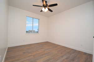 Room featuring wood-finish flooring, white baseboards, and a window with blinds