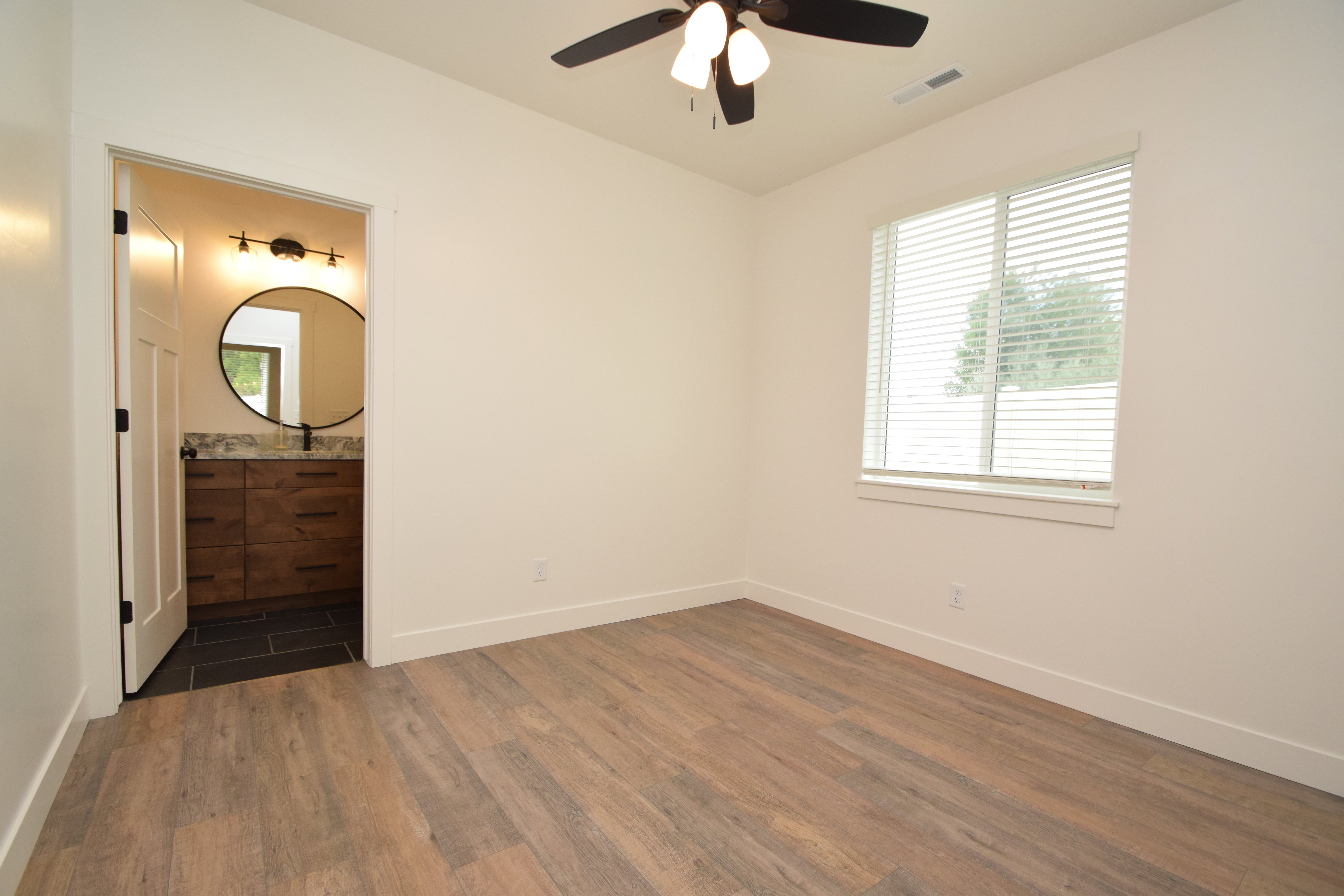 Spacious room featuring wood-finish flooring and a ceiling fan