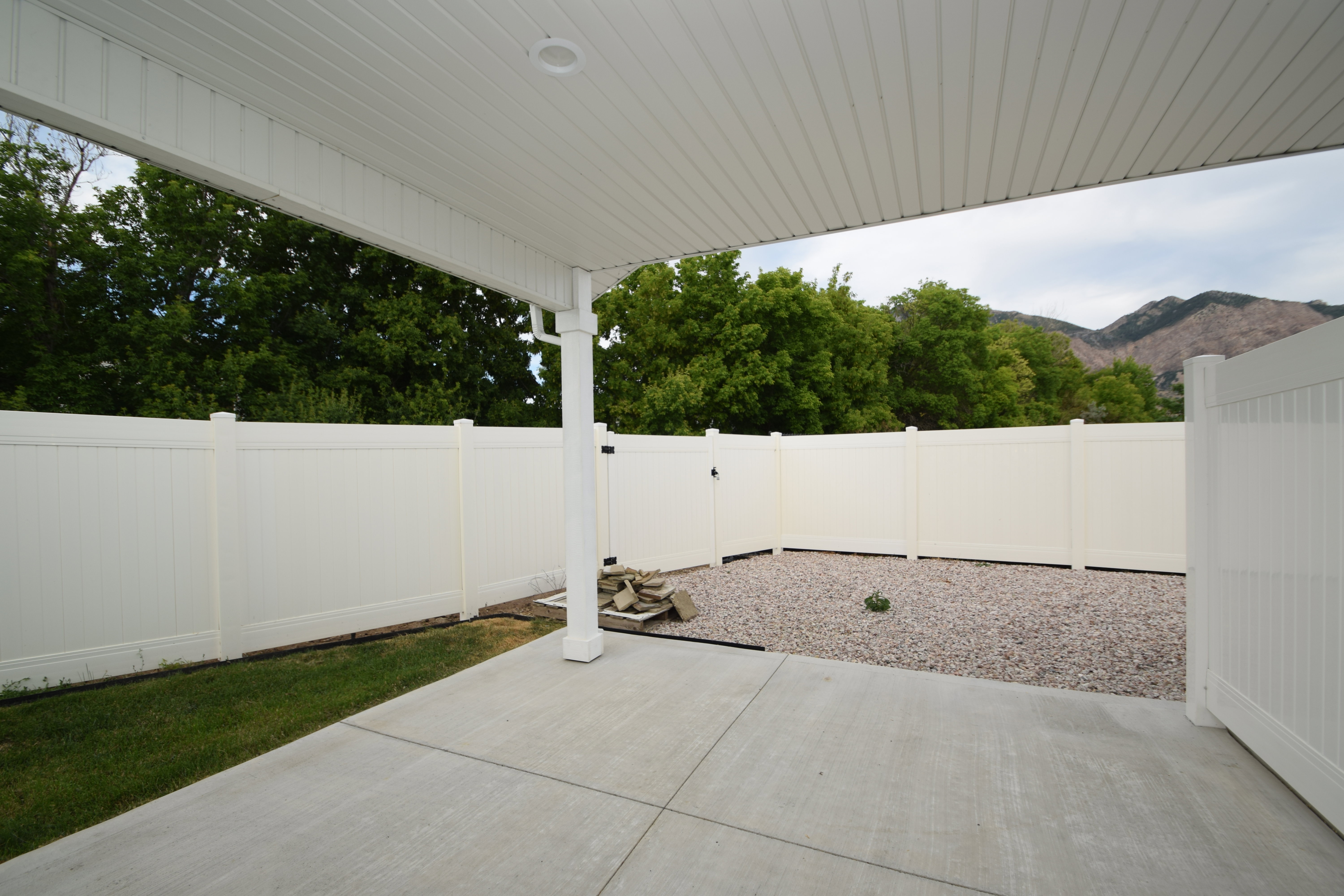 Covered patio featuring a concrete slab and a white vinyl privacy fence