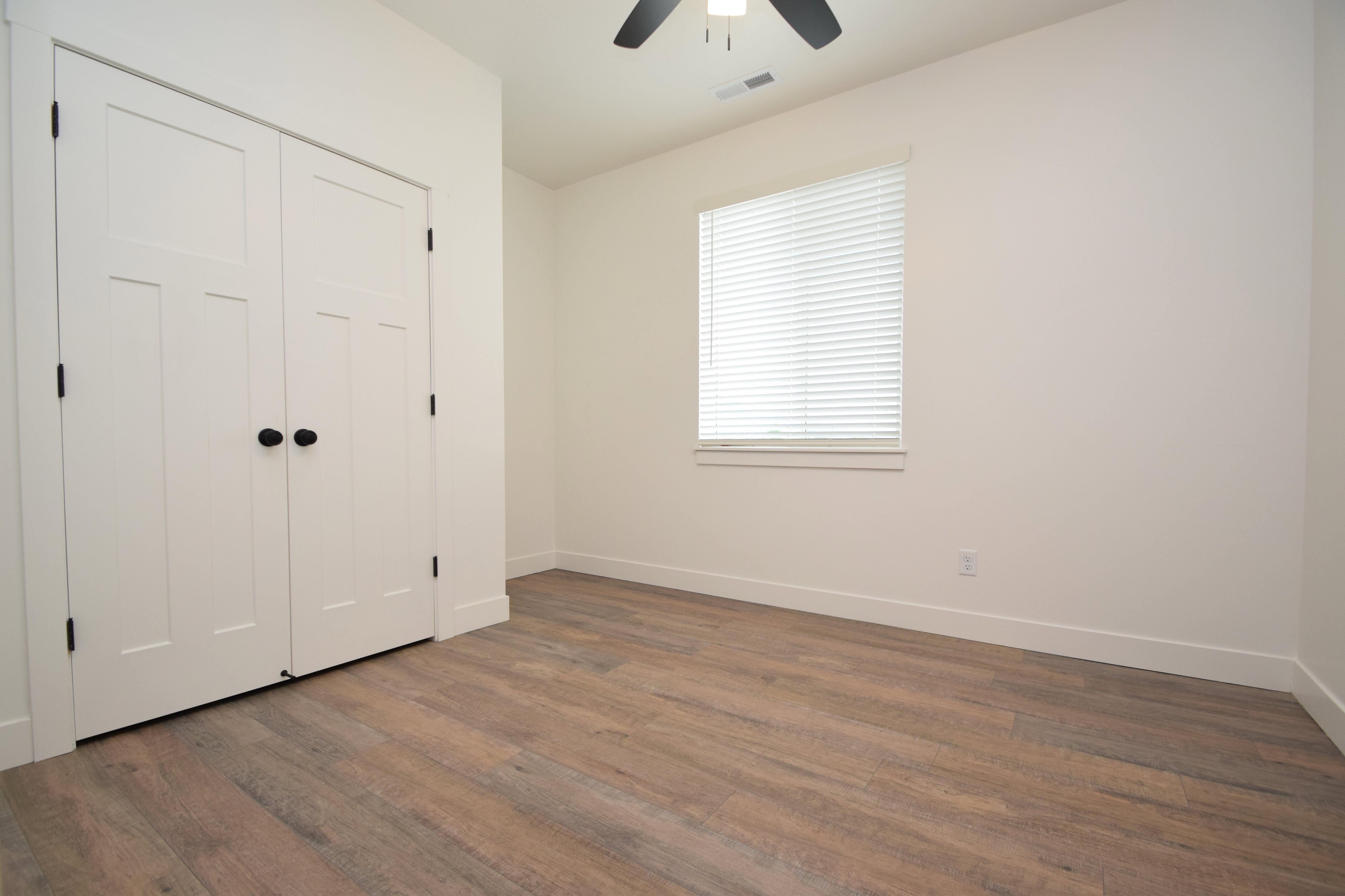 Interior room with wood-finish flooring, white walls, and a white trim package
