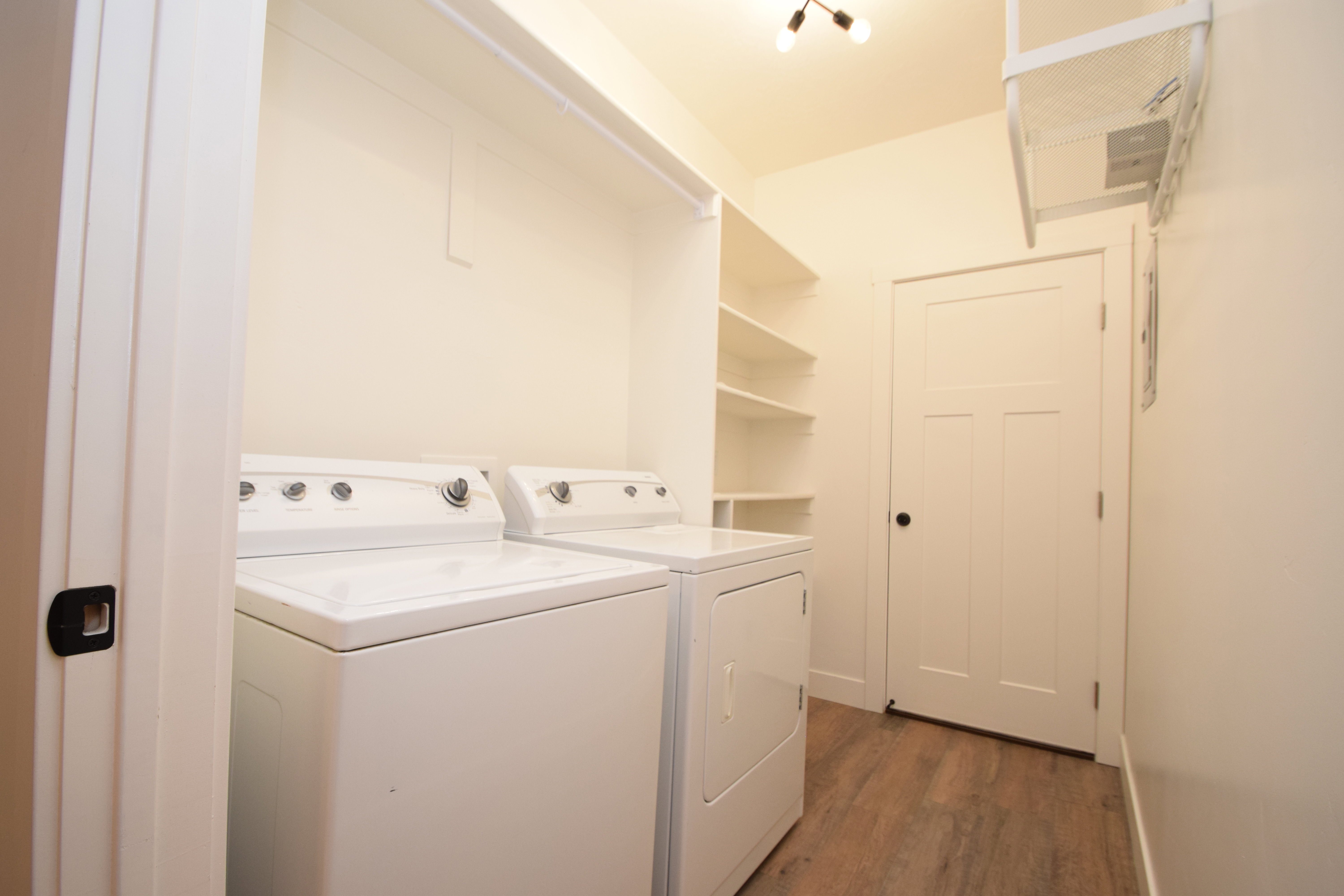 Dedicated laundry area featuring a washer and dryer, built-in shelving, wood-finish flooring, and recessed lighting