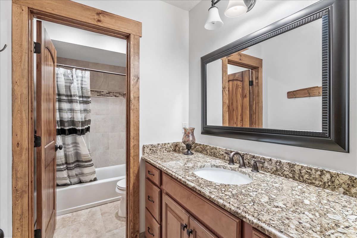 Bathroom vanity featuring a granite countertop, undermount sink, and dark bronze hardware