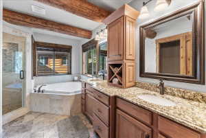 Bathroom featuring exposed wood beams, a corner jetted tub, and a separate glass-enclosed shower with stone tile