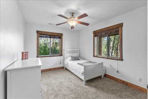 Bedroom featuring white walls, textured carpeting, and wood-trimmed windows
