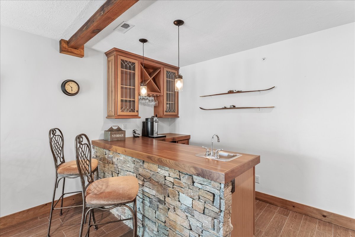 Custom wet bar featuring a stone-clad base, wood-finish countertop, and integrated sink