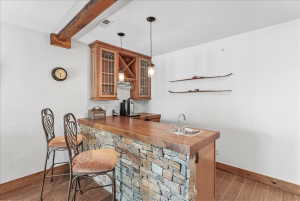 Custom wet bar featuring a stone-clad base, wood-finish countertop, and integrated sink