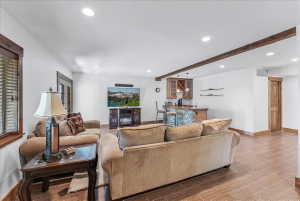 Spacious entertainment area featuring wood-finish flooring, recessed lighting, and exposed ceiling beams