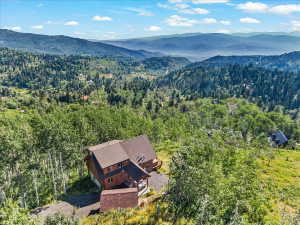 Mountain-side residence featuring a multi-level structure with natural wood siding and a brown shingle roof