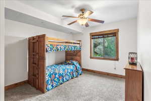 Carpeted room featuring a window with natural wood trim, a ceiling fan, and white painted walls
