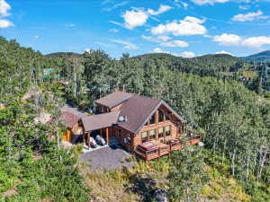 Log-sided residence featuring a multi-level deck, a prominent A-frame window design, and an attached covered carport