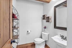 Powder room featuring a pedestal sink with a brushed nickel faucet, a framed mirror, and a toilet