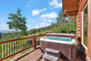 Deck featuring a built-in hot tub with a protective cover, a two-step entry, and wood-finish railings