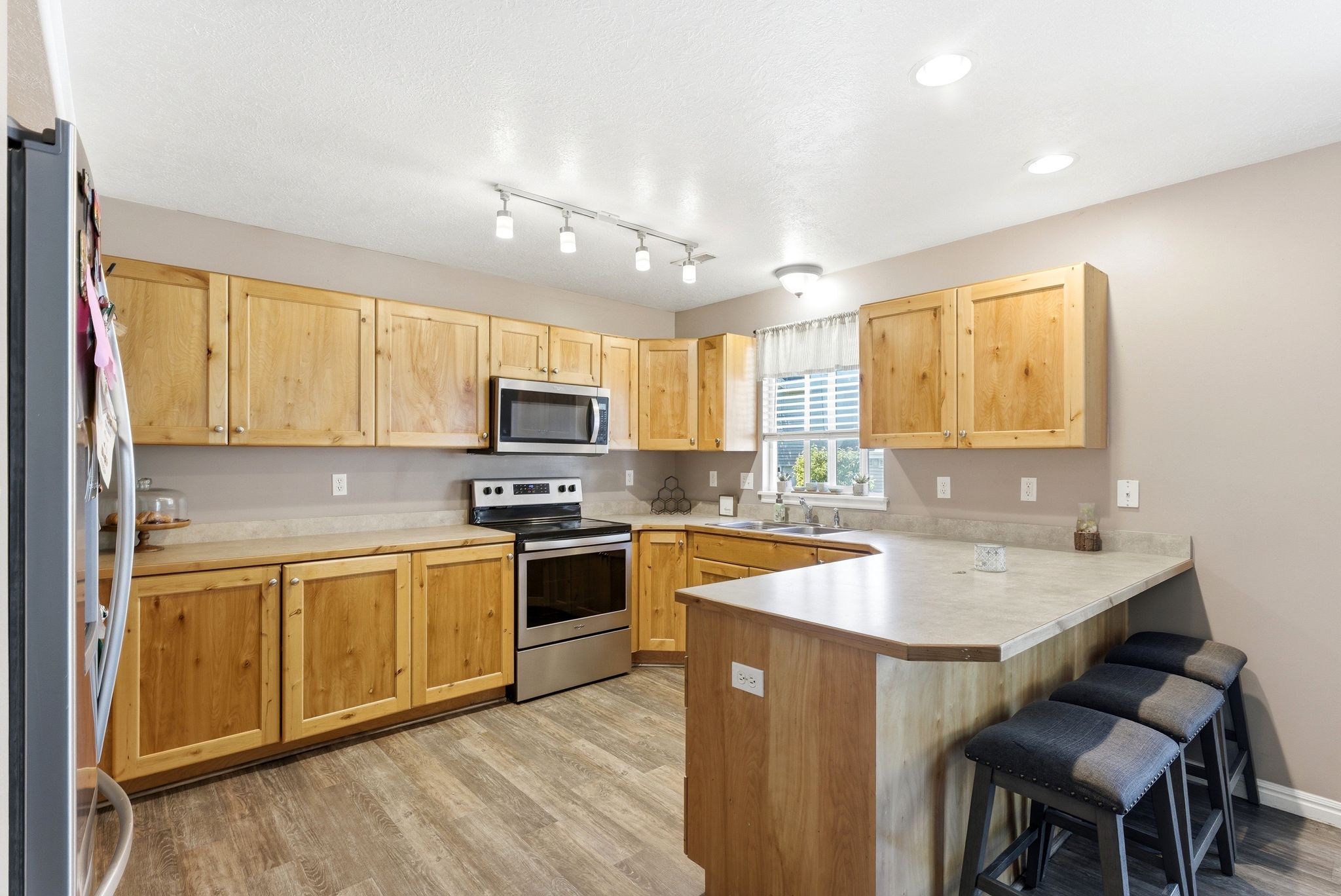 Kitchen featuring wood-finish cabinetry, stainless steel appliances, laminate countertops, and wood-finish flooring