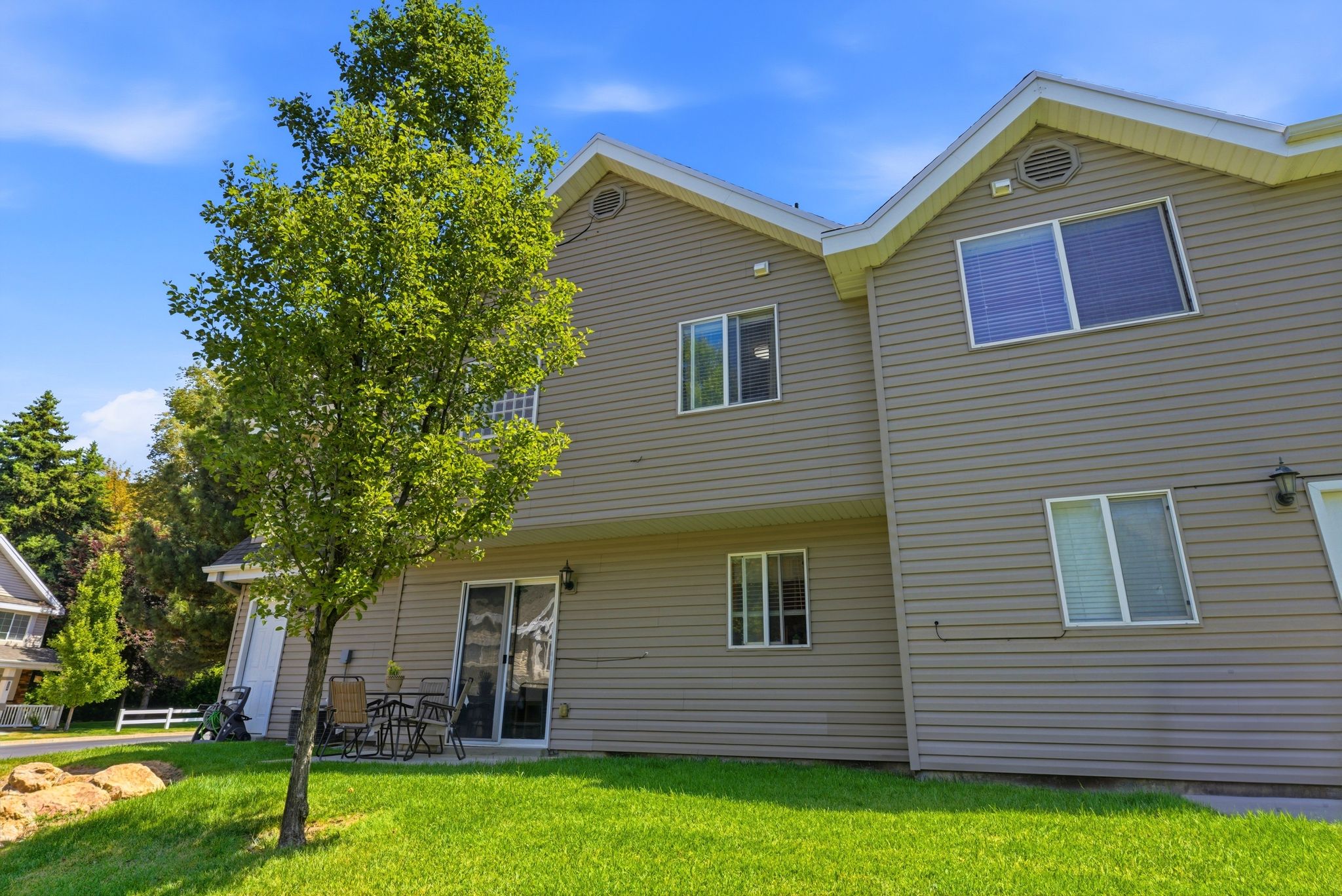 Exterior rear elevation featuring horizontal siding, multiple windows, and a sliding glass door opening to a concrete patio