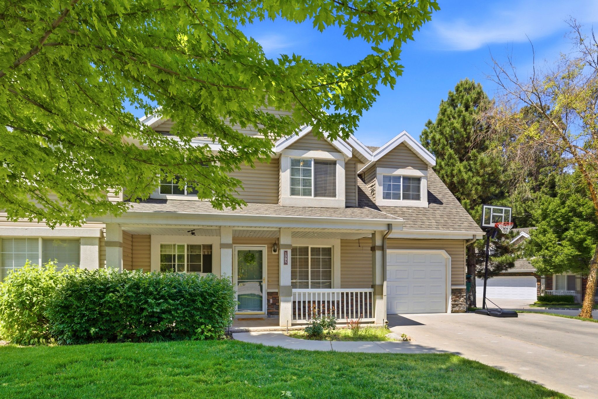 Light-colored siding exterior with a covered porch, white railing, and stone accents