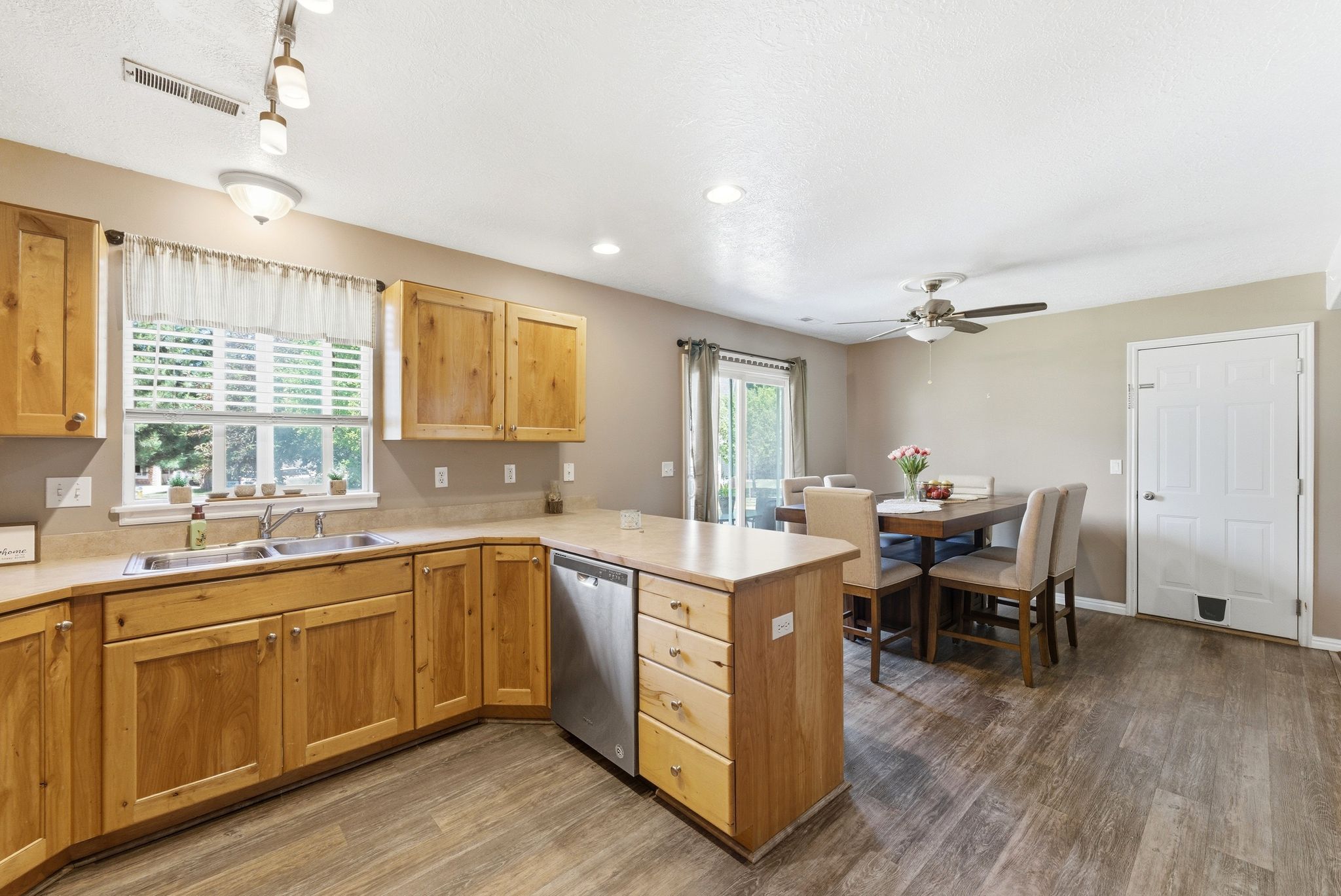 Kitchen area featuring natural wood cabinetry, stainless steel dishwasher, and wood-finish flooring