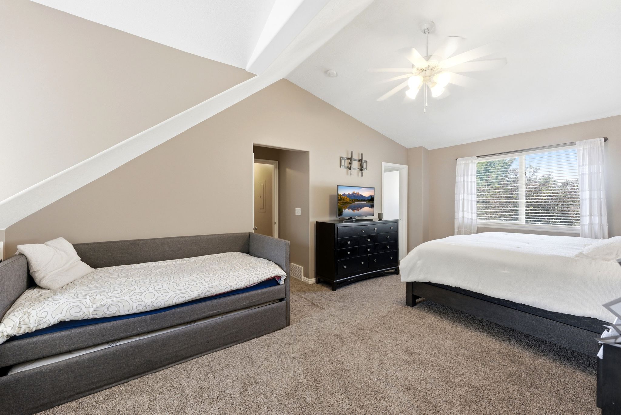 Spacious room featuring vaulted ceilings, a ceiling fan with integrated lighting, window blinds, and neutral-toned wall paint
