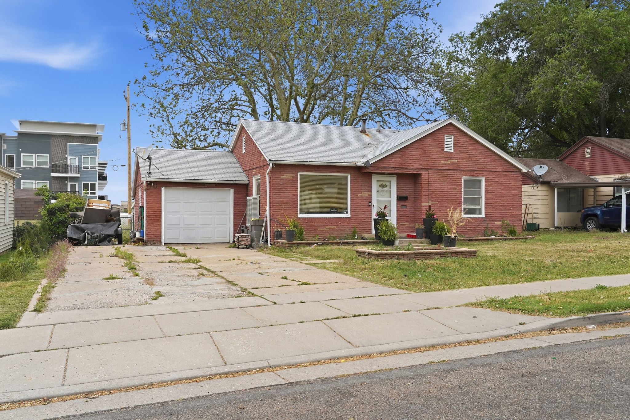 Red brick exterior with a front-facing window, an attached single-car garage, concrete driveway, and a sidewalk