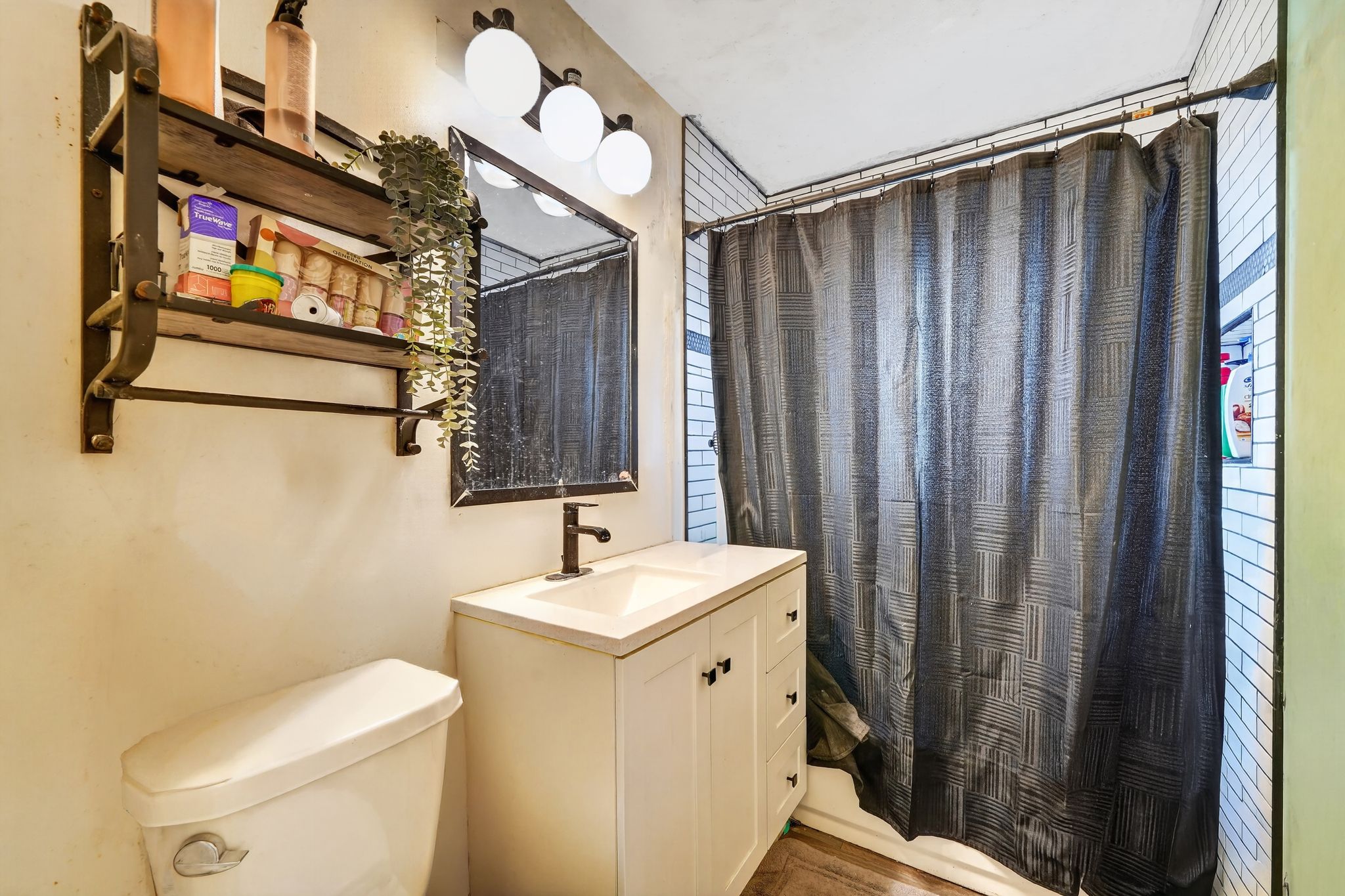 Bathroom featuring a white vanity with a rectangular sink, black faucet, and a wall-mounted mirror