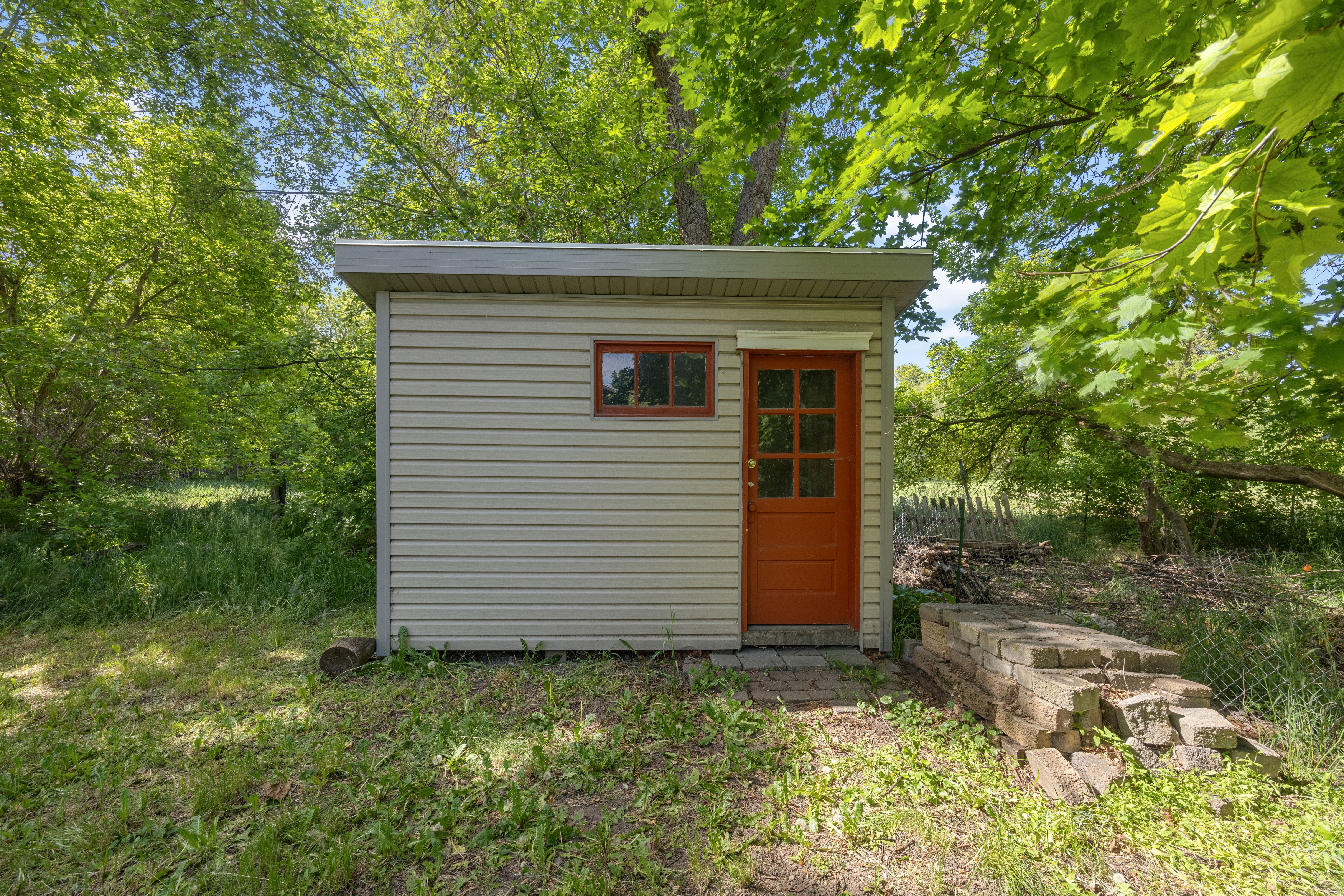 Exterior shed with horizontal siding, a flat roof, and an orange paneled door