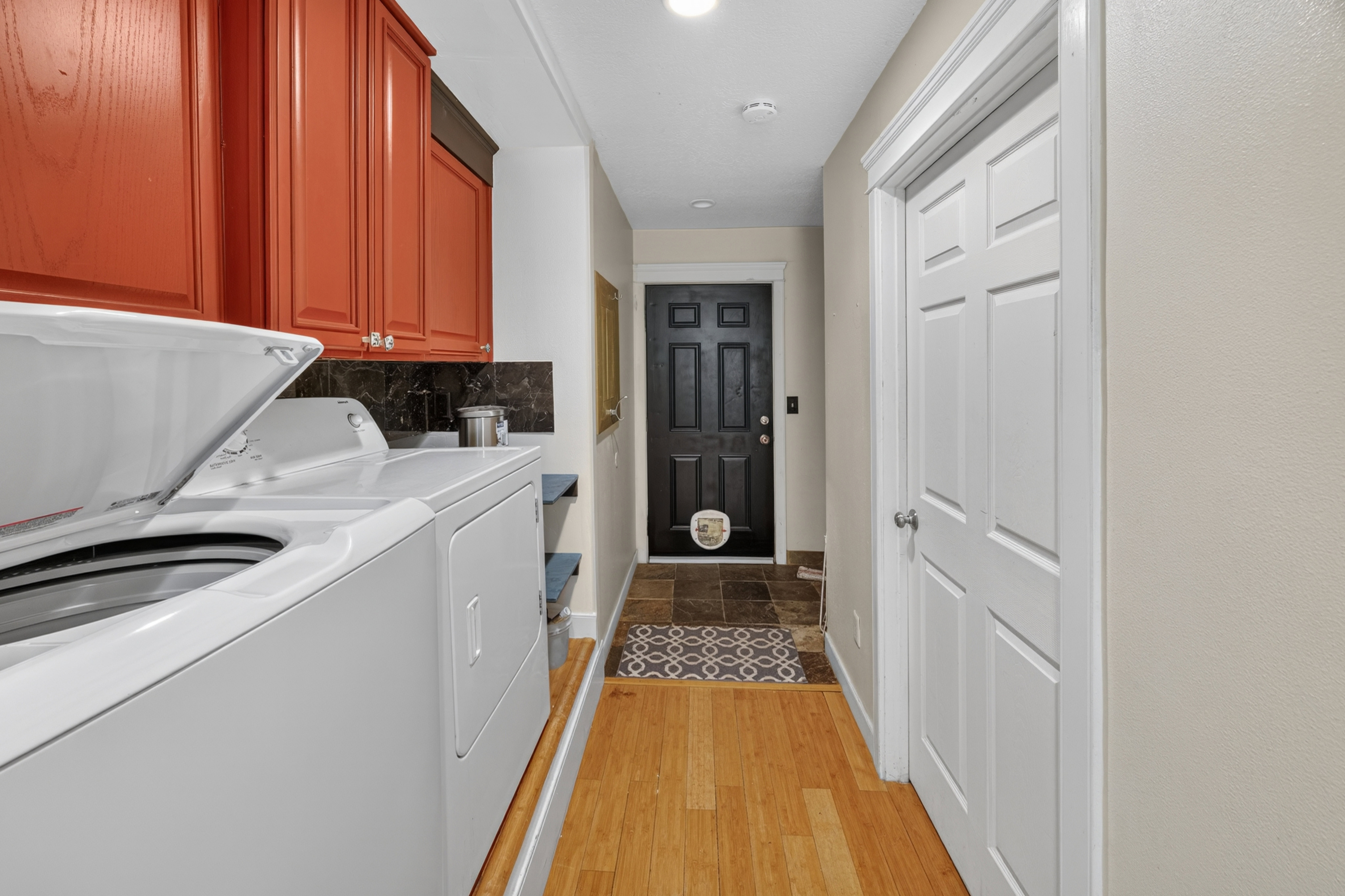 Functional laundry area featuring upper cabinetry in a warm wood tone