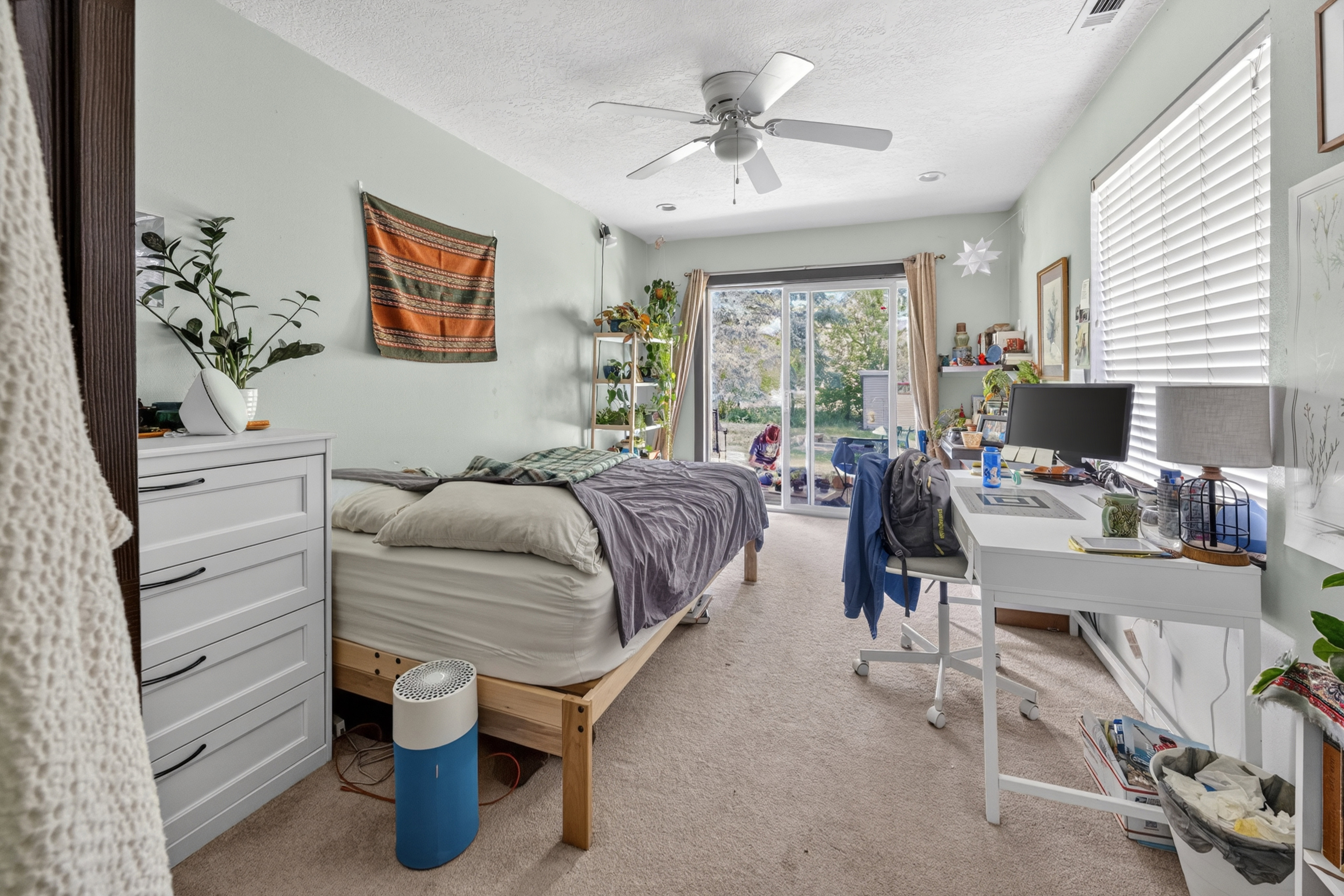 Room featuring light-colored carpeting, a ceiling fan, and sliding glass doors providing access to the exterior