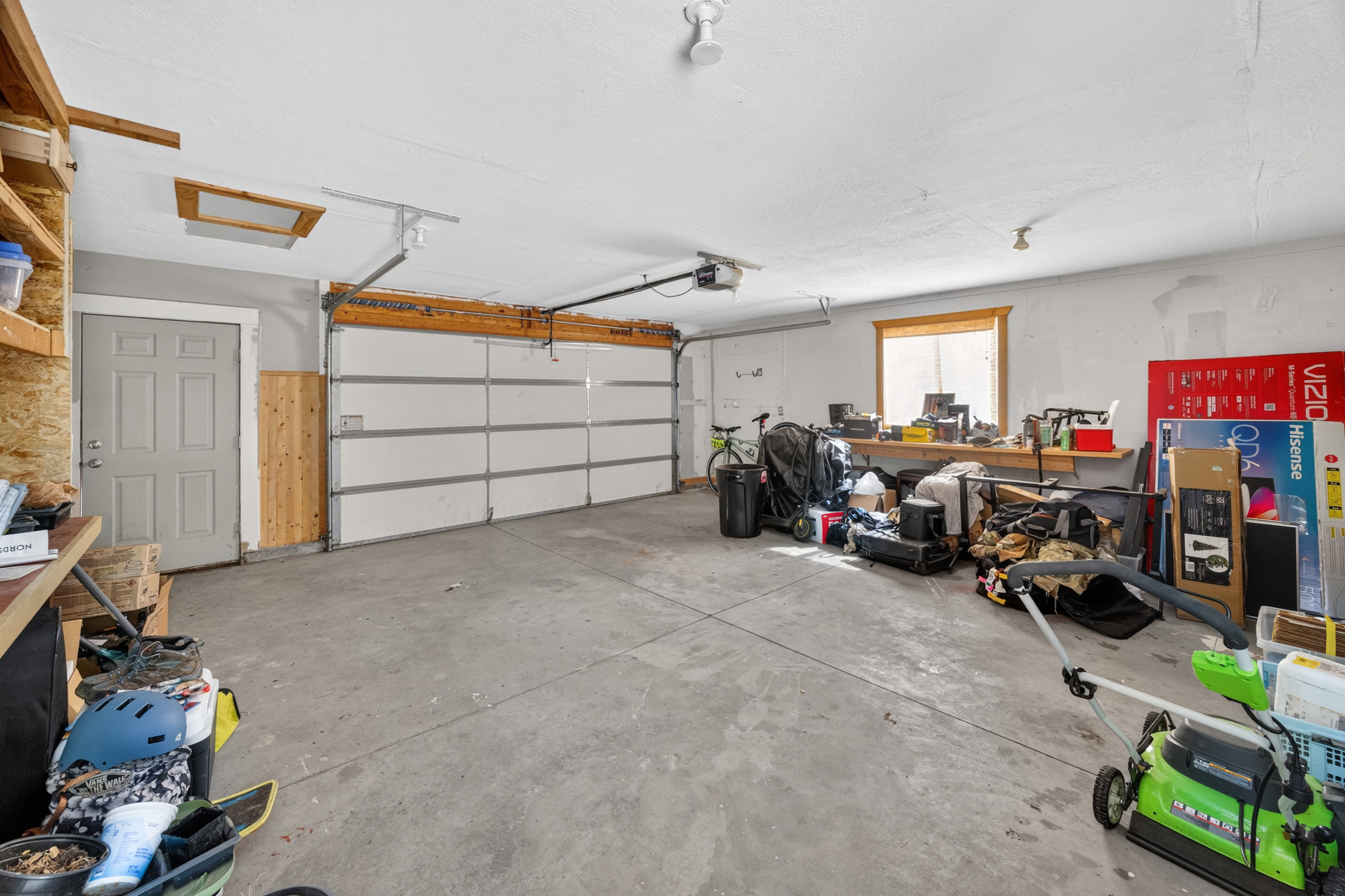 Spacious garage with a concrete floor, overhead lighting, and a window for natural illumination