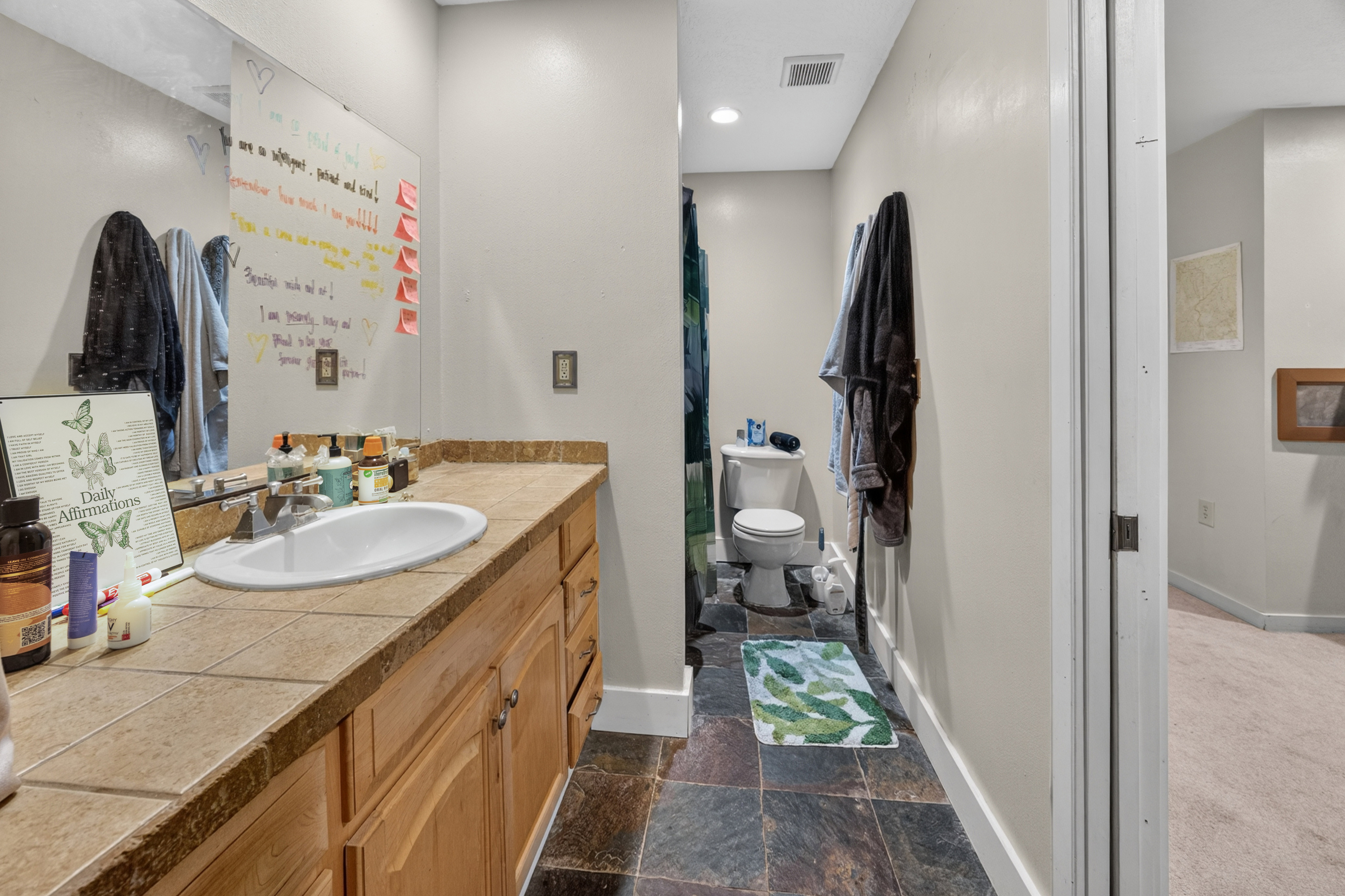 Bathroom vanity featuring a single basin sink, tile countertop, and wood cabinetry
