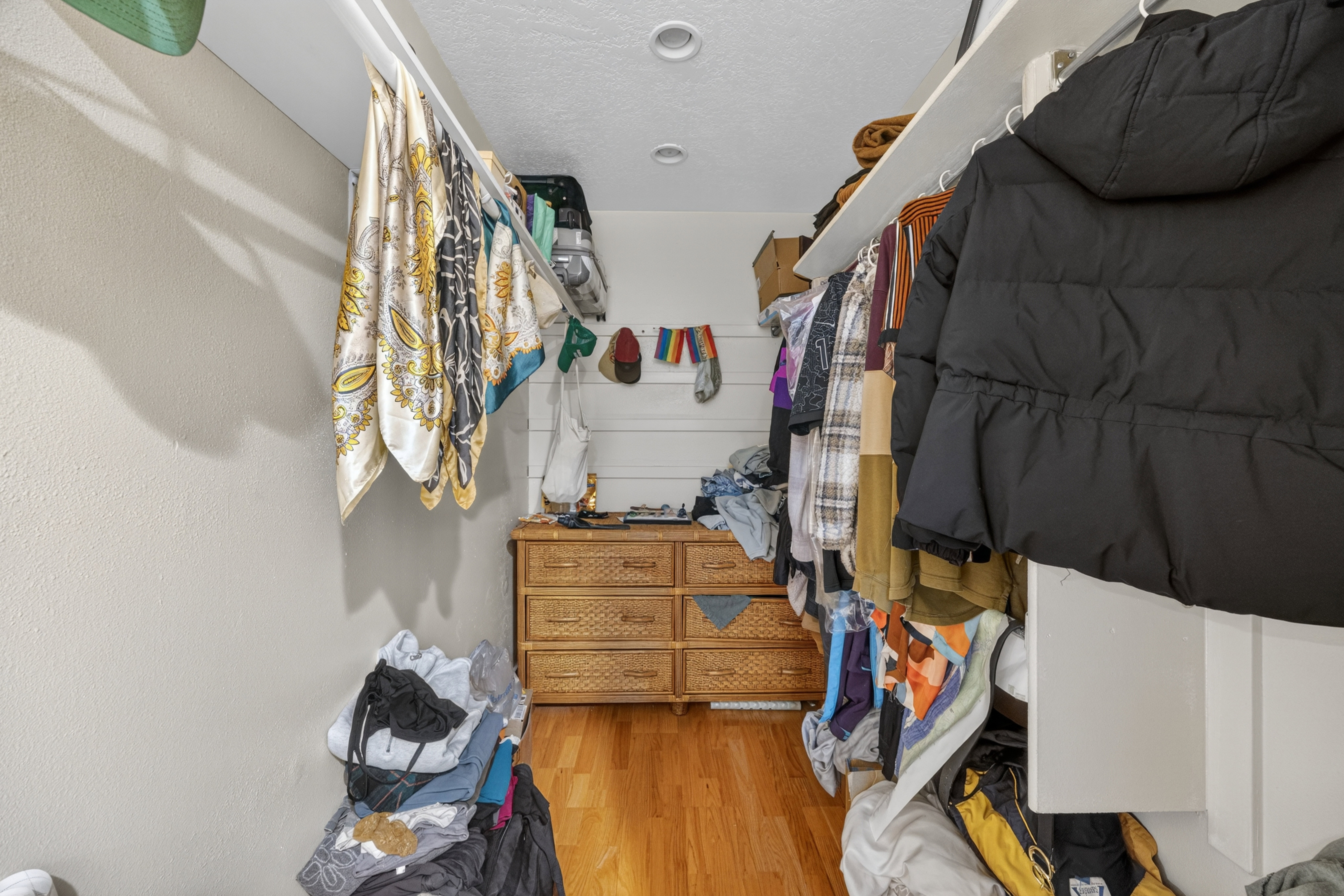 Walk-in closet featuring recessed lighting, a built-in dresser with wicker drawer fronts, and wood-finish flooring