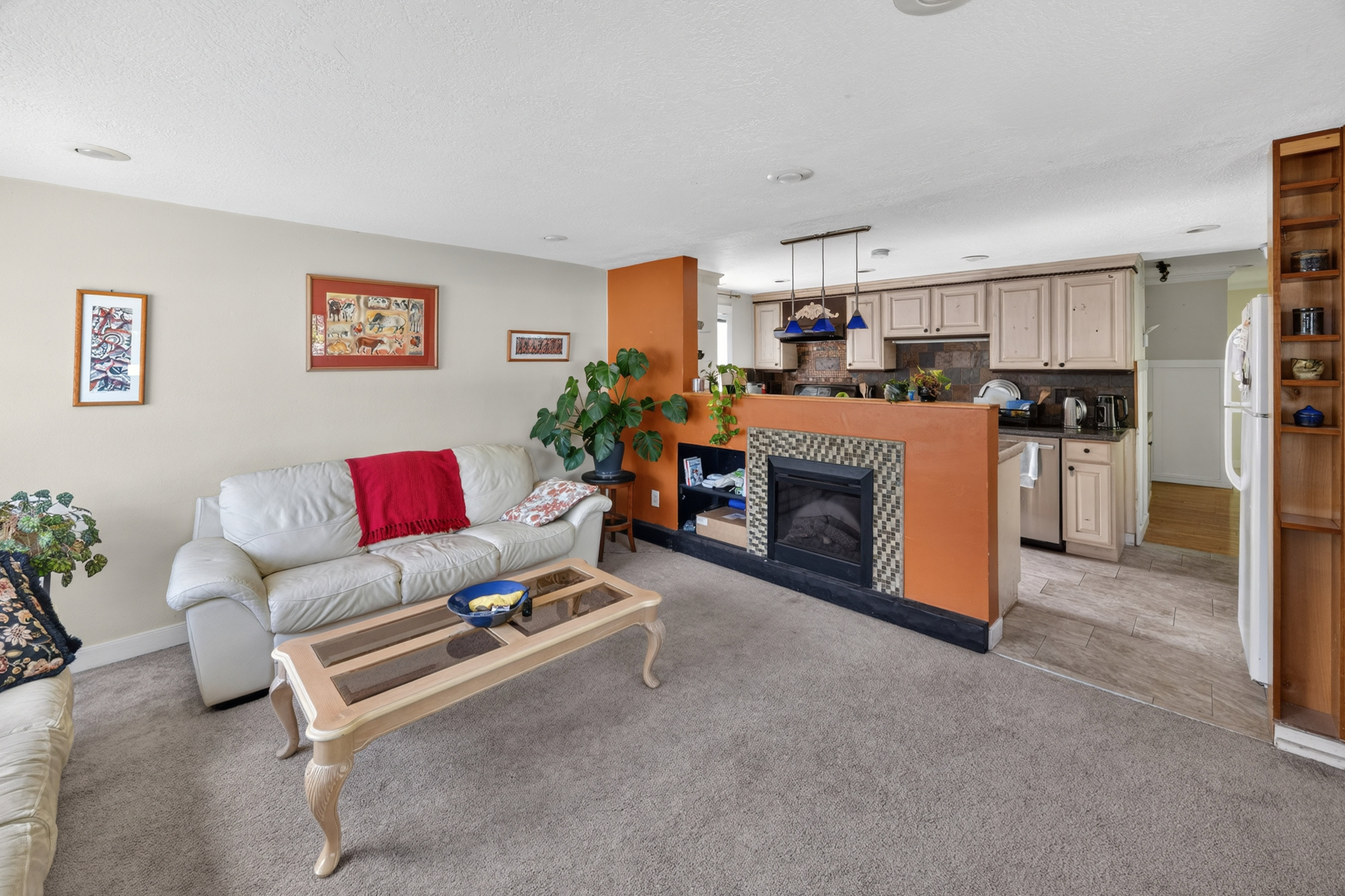 Open-concept living area with carpeted flooring and a built-in electric fireplace featuring decorative tile surround