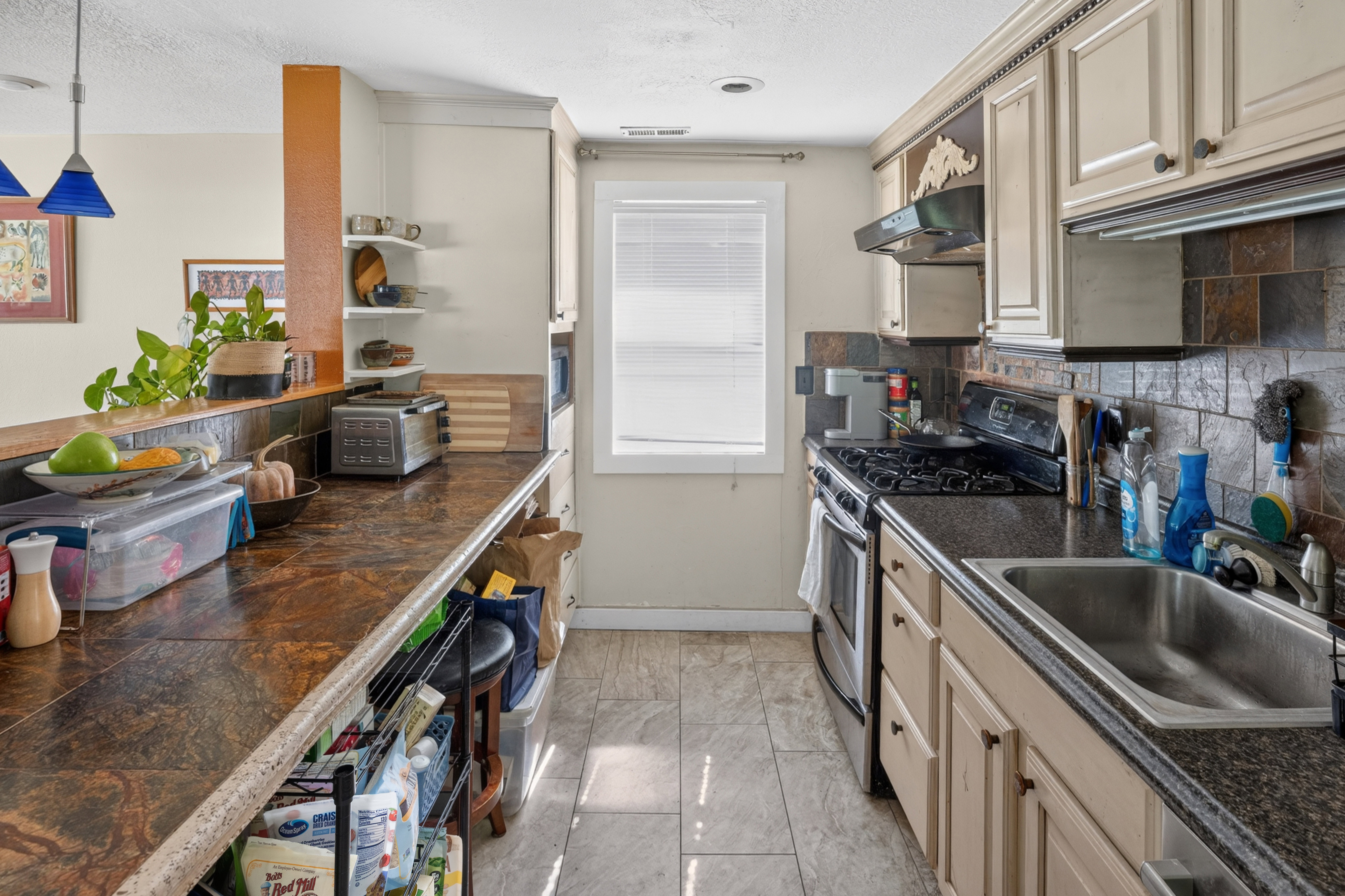 Galley-style kitchen featuring granite-look countertops, subway tile backsplash, and light-toned cabinetry