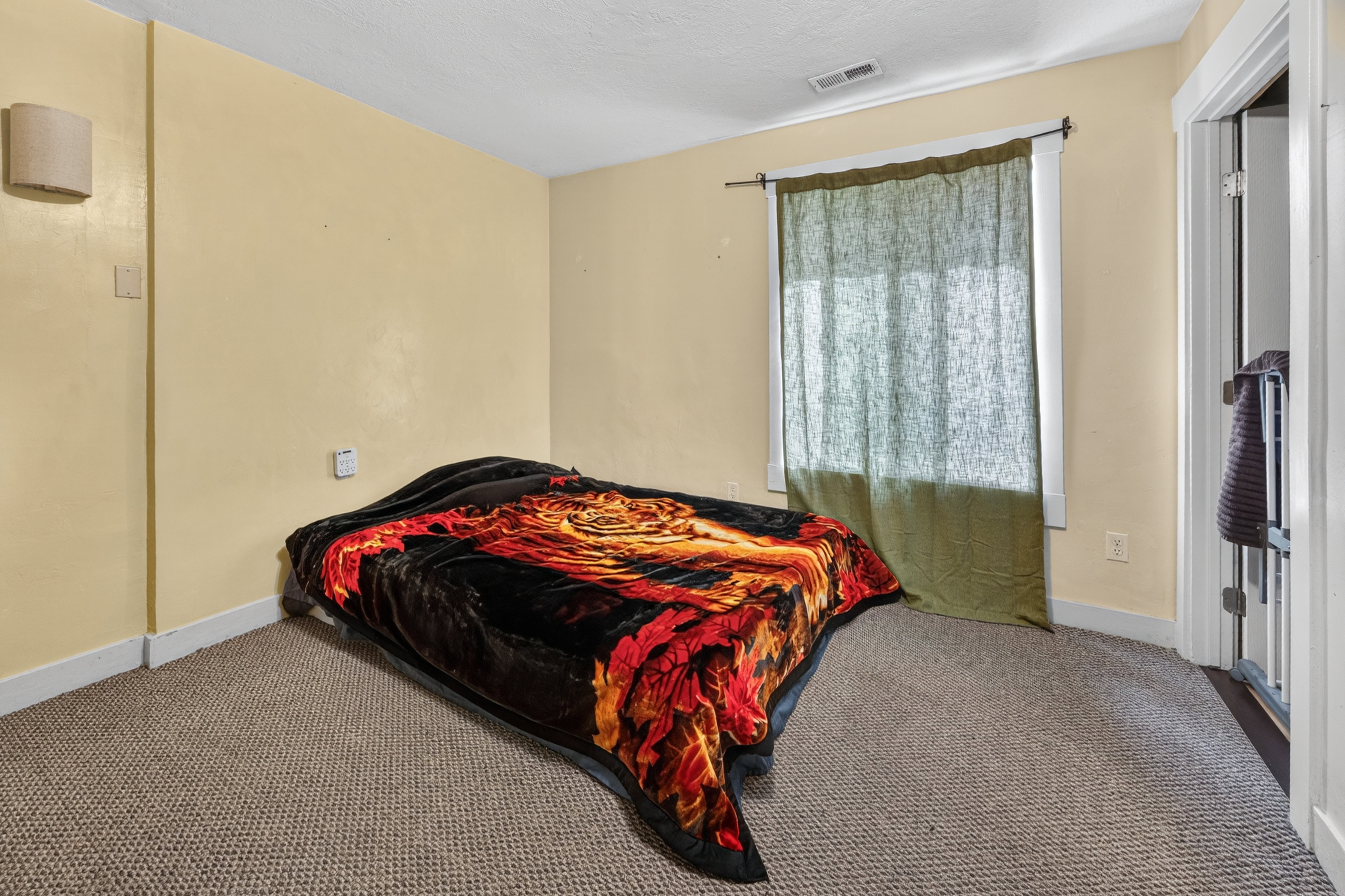 Carpeted room featuring a window with a curtain rod, baseboard trim, and a wall-mounted light fixture