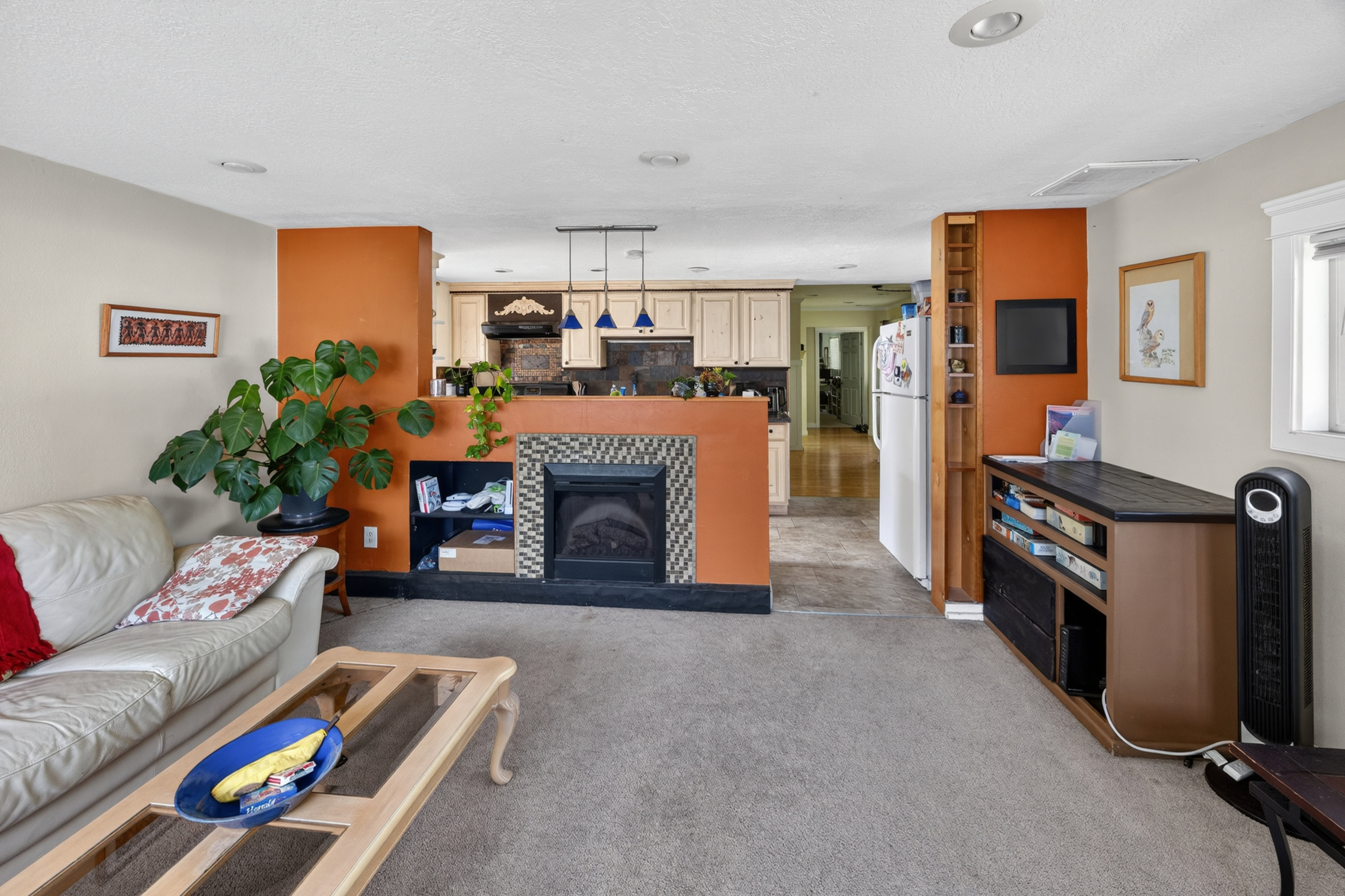 Living area featuring a built-in fireplace with a tiled surround, recessed lighting, and a built-in shelving unit
