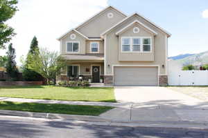 Two-story stucco exterior featuring stone accents, a two-car garage, a concrete driveway, RV parking a manicured lawn, and mature landscaping