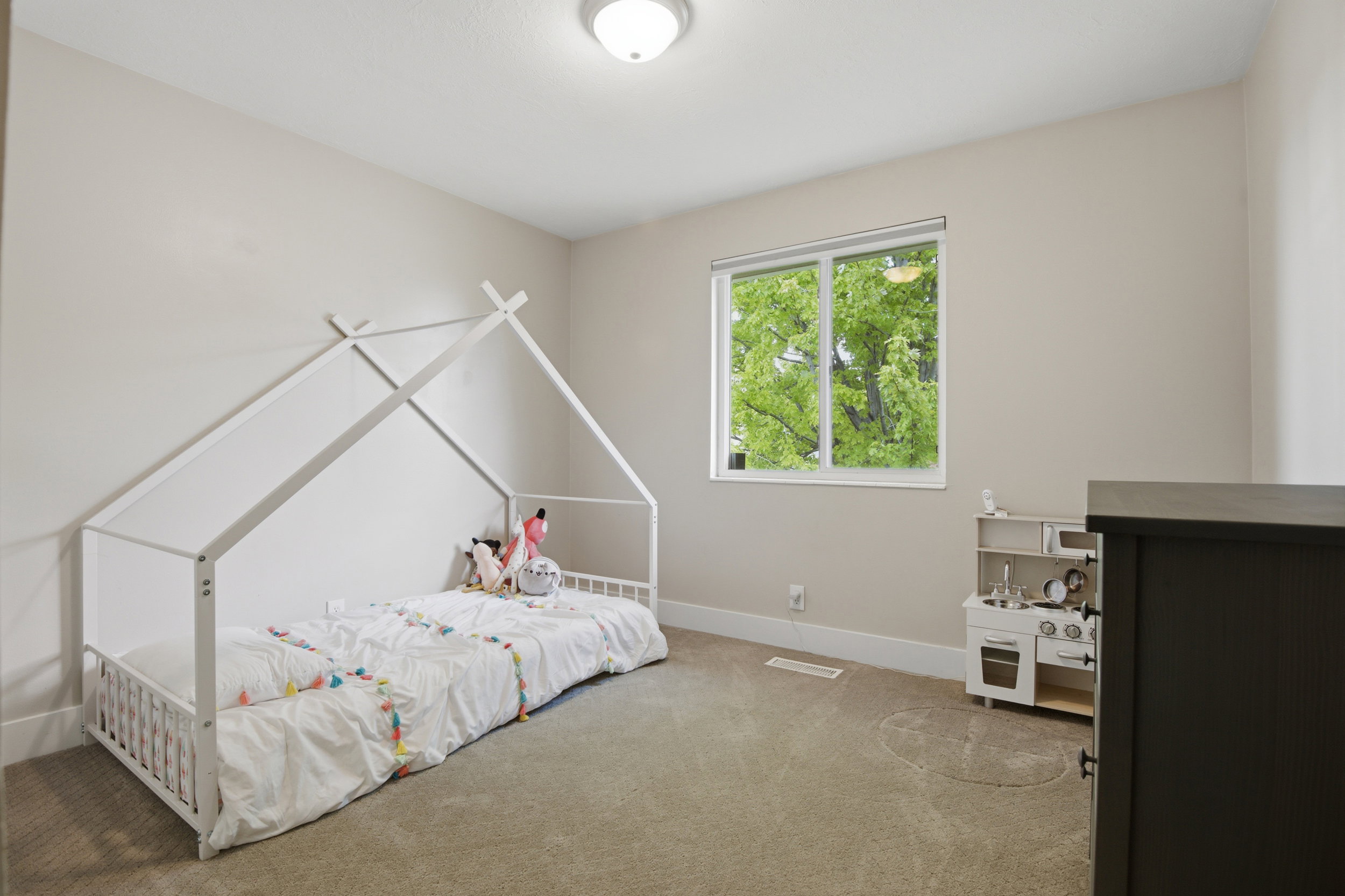 Bedroom featuring light neutral wall paint, carpet flooring, a large window, and a ceiling-mounted light fixture