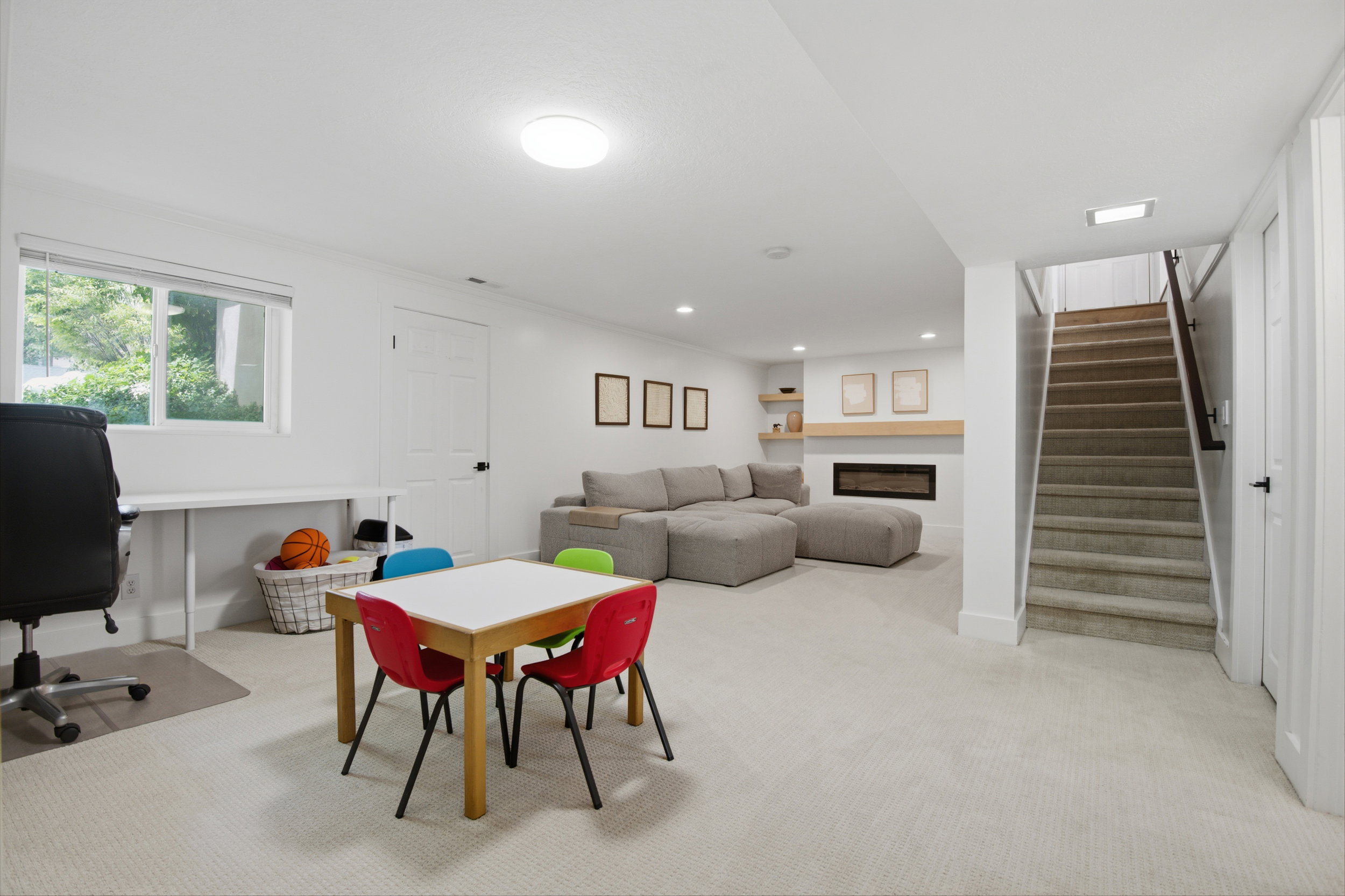Spacious lower-level living area with recessed lighting, a built-in electric fireplace with wood mantel, and plush carpeting