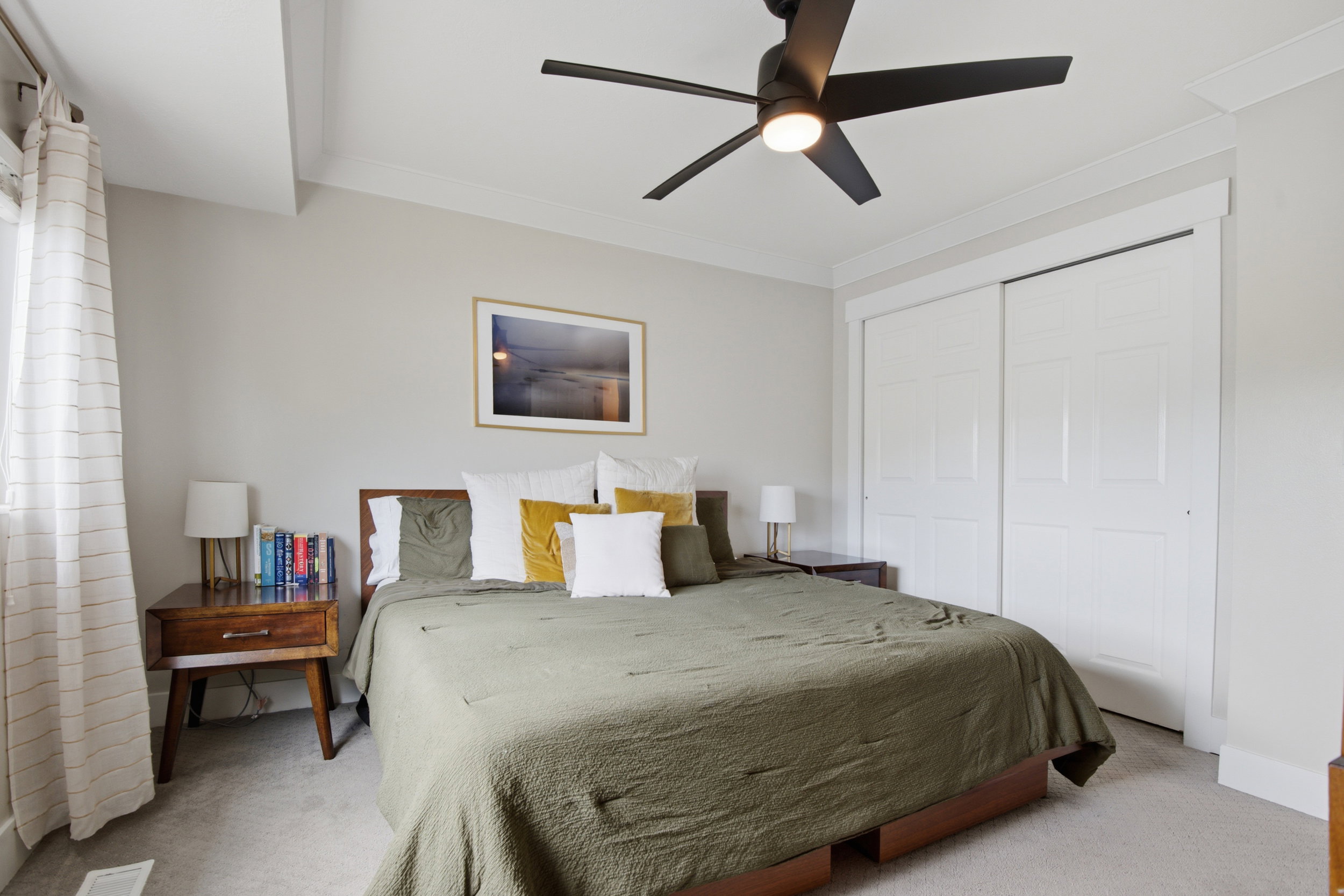 Spacious room featuring a contemporary ceiling fan with integrated lighting, a large window, crown molding, and two-panel sliding closet doors