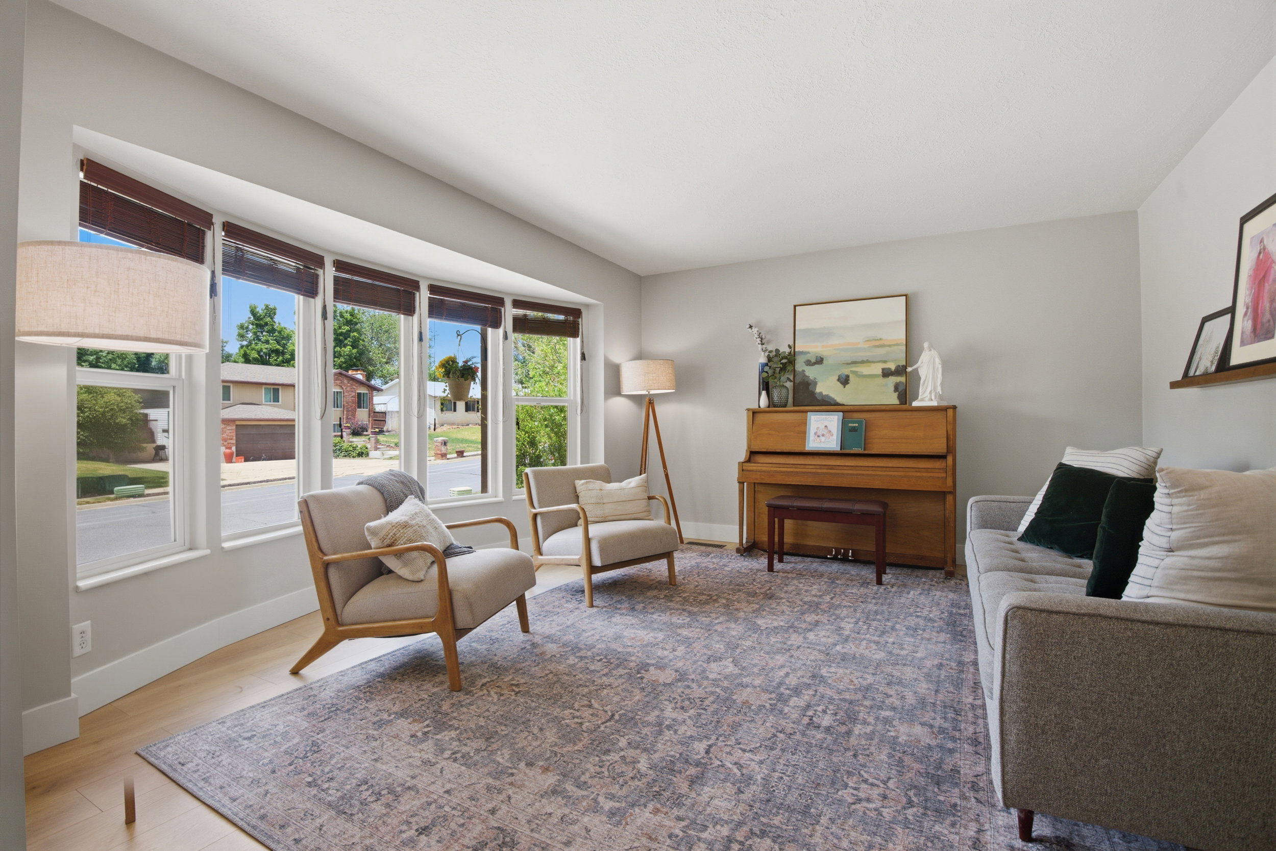 Bright living area featuring a large bay window with multiple panes, light wood-finish flooring, and light gray wall paint